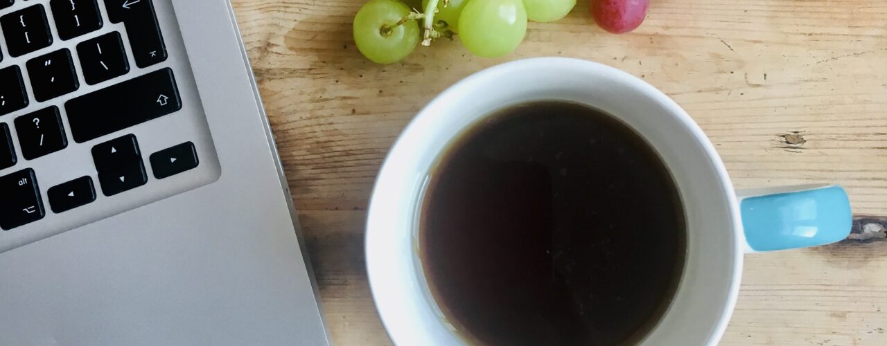 Laptop, coffee cup and grapes on a desk